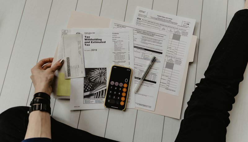 Documentos de factura con cálculo de IVA y retención IRPF sobre escritorio